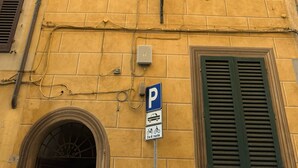 A yellow building with green shutters, a street lamp, and a parking sign. - Pendulum - 9 (Siena)