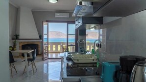 Eine moderne Küche mit Meerblick, ein Essbereich mit Tisch und Stühlen sowie ein Kamin.
