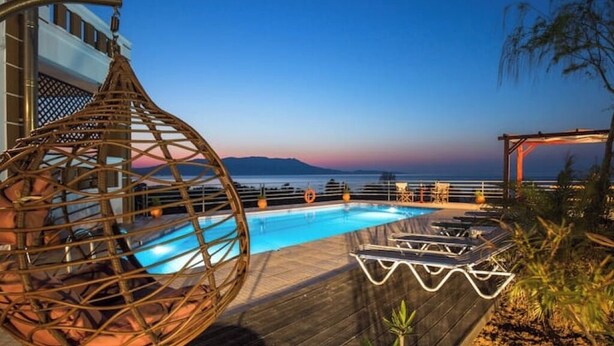 Ein Poolbereich mit Holzterrasse, Liegestühlen und einem Korbsessel.