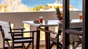 Ein Balkon mit Tisch, Stühlen und Blick auf das Meer.