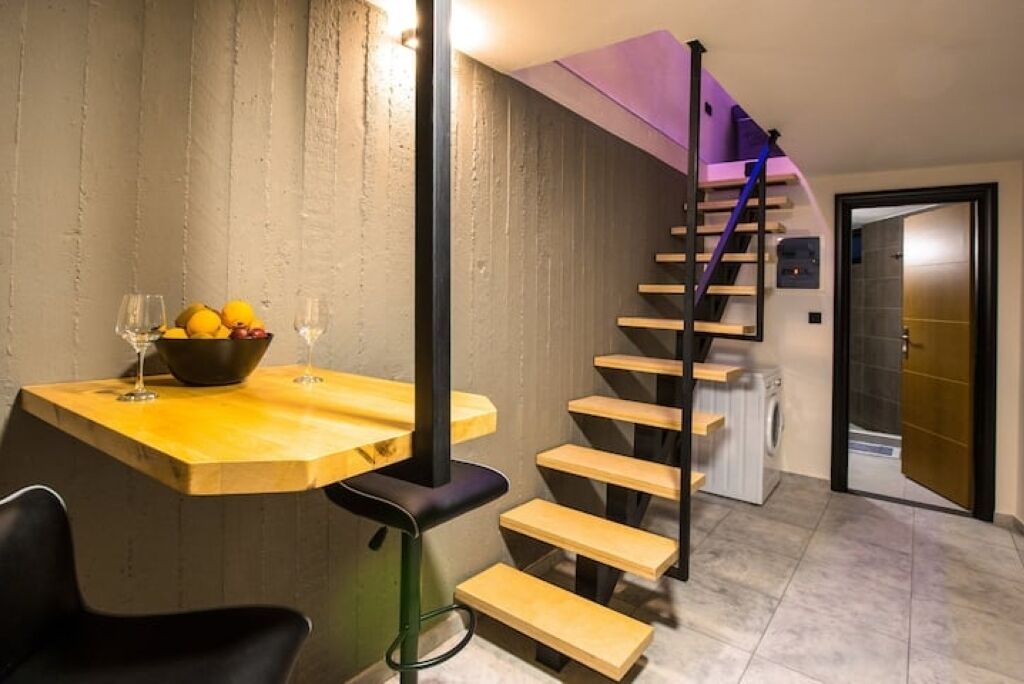 Een modern interieur met een houten eettafel, een zwarte stoel en een trap met houten treden en een paars accent.