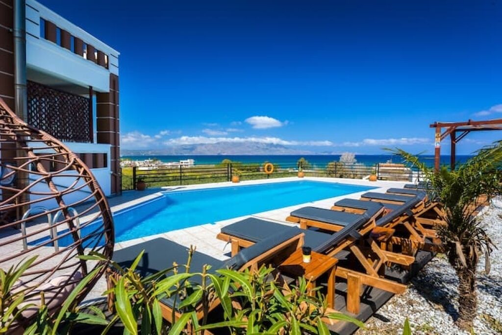 A rooftop pool with lounge chairs and a view of the ocean.