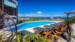 A rooftop pool with lounge chairs and a view of the ocean. - Relax in Style at Ben’s Homes Panorama (Nopigia)