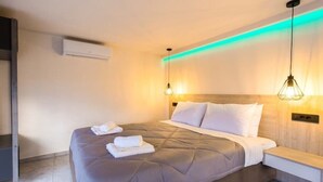 A modern hotel room with a large bed, bedside tables, and ambient lighting. - Relax in Style at Ben’s Homes Panorama (Nopigia)