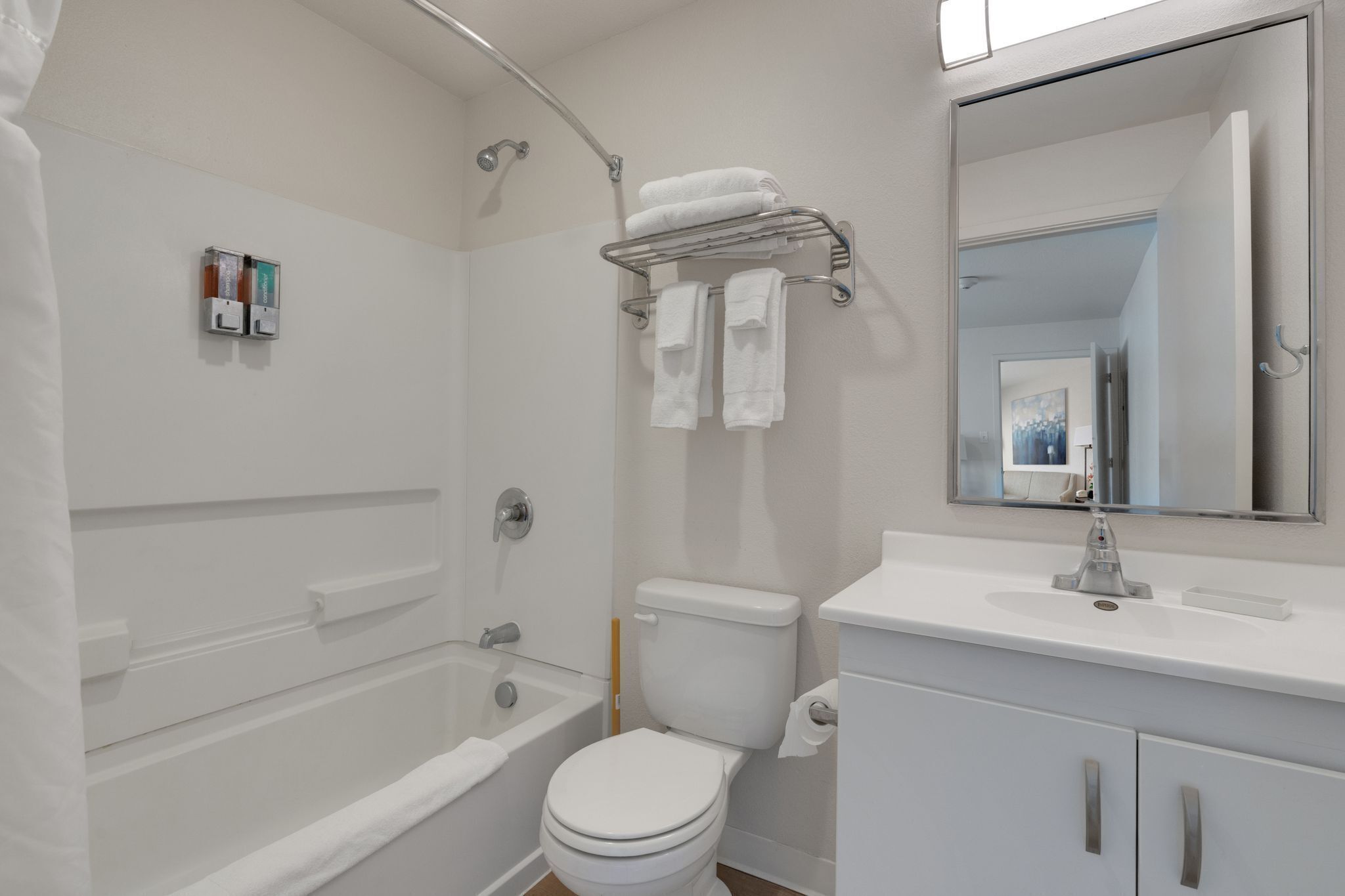A modern bathroom with a bathtub, toilet, and a vanity with a mirror.