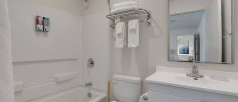 A modern bathroom with a bathtub, toilet, and a vanity with a mirror.