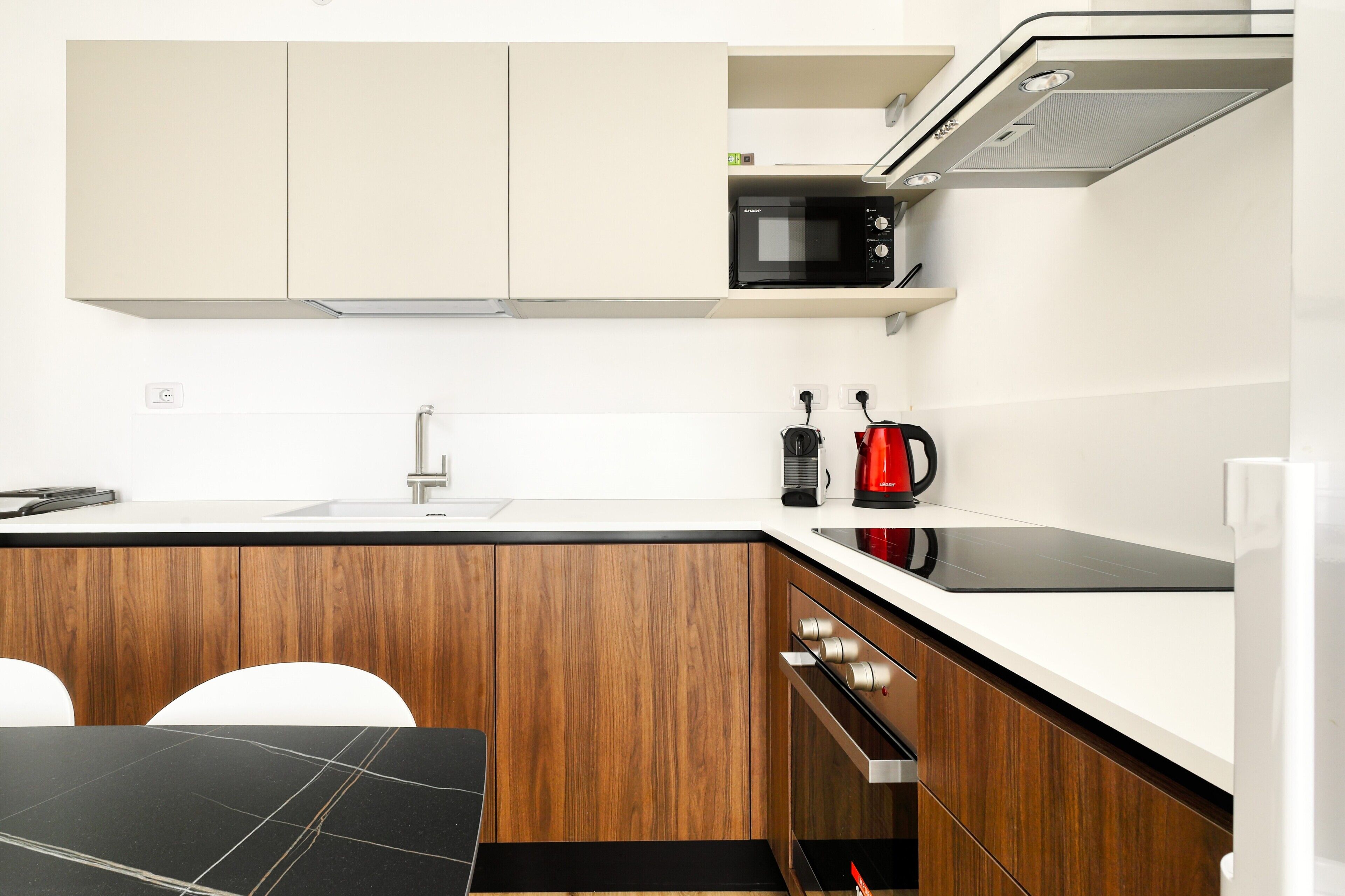 A modern kitchen with wooden cabinets, a black countertop, a built-in microwave, and a coffee maker.