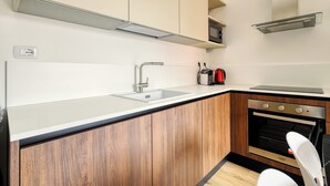 A modern kitchen with a built-in oven, a sink, and wooden cabinetry. - 1-Bed apartment with balcony near subway (Milan)