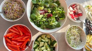 A table with various food items including salads, vegetables, and condiments.