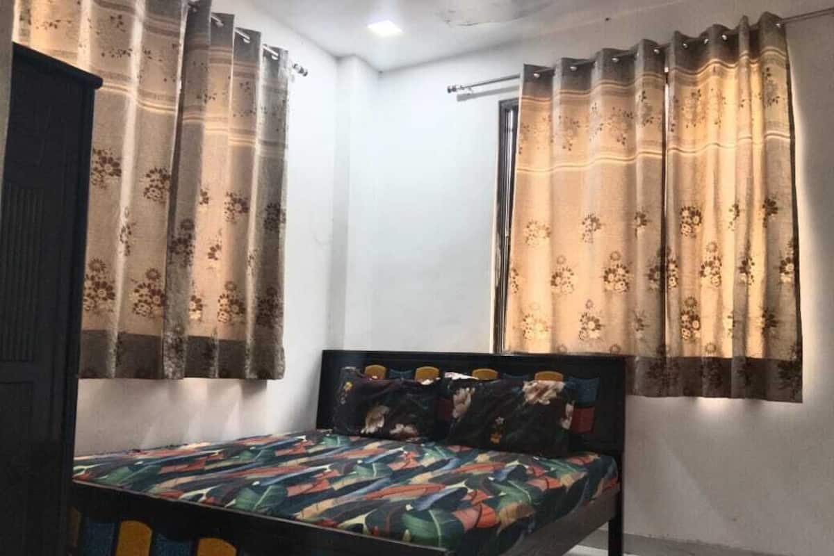 A bedroom with a bed, curtains, and a window.