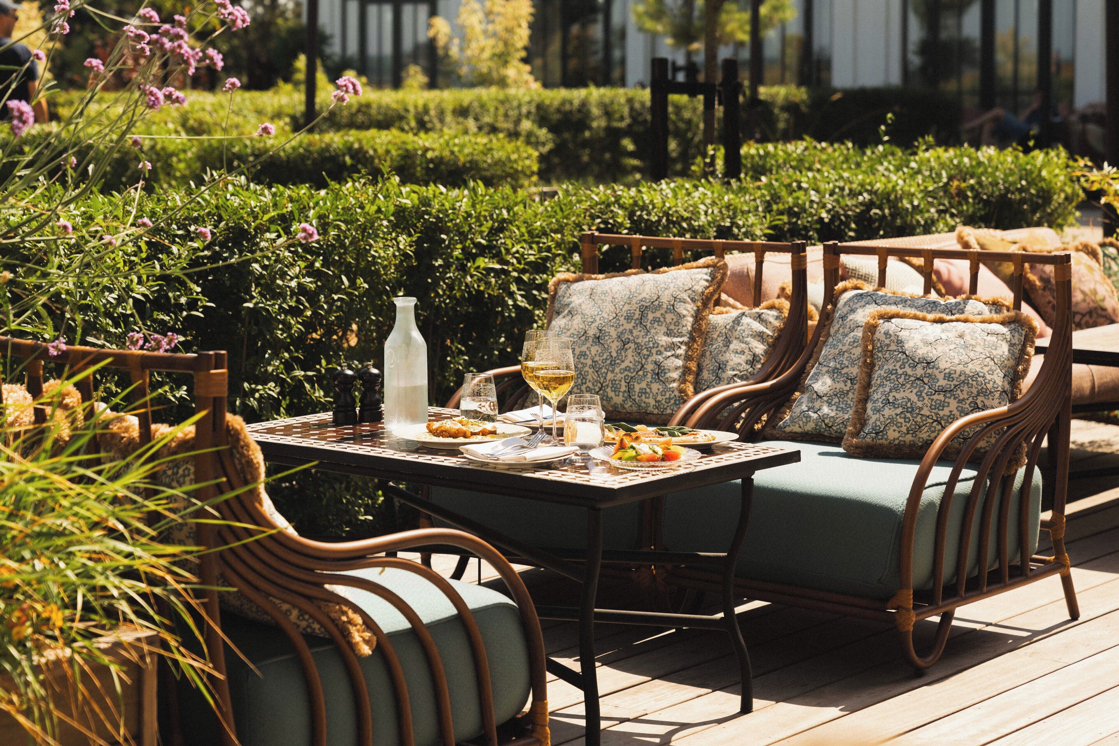 An outdoor dining area with wicker furniture and a table set for two.