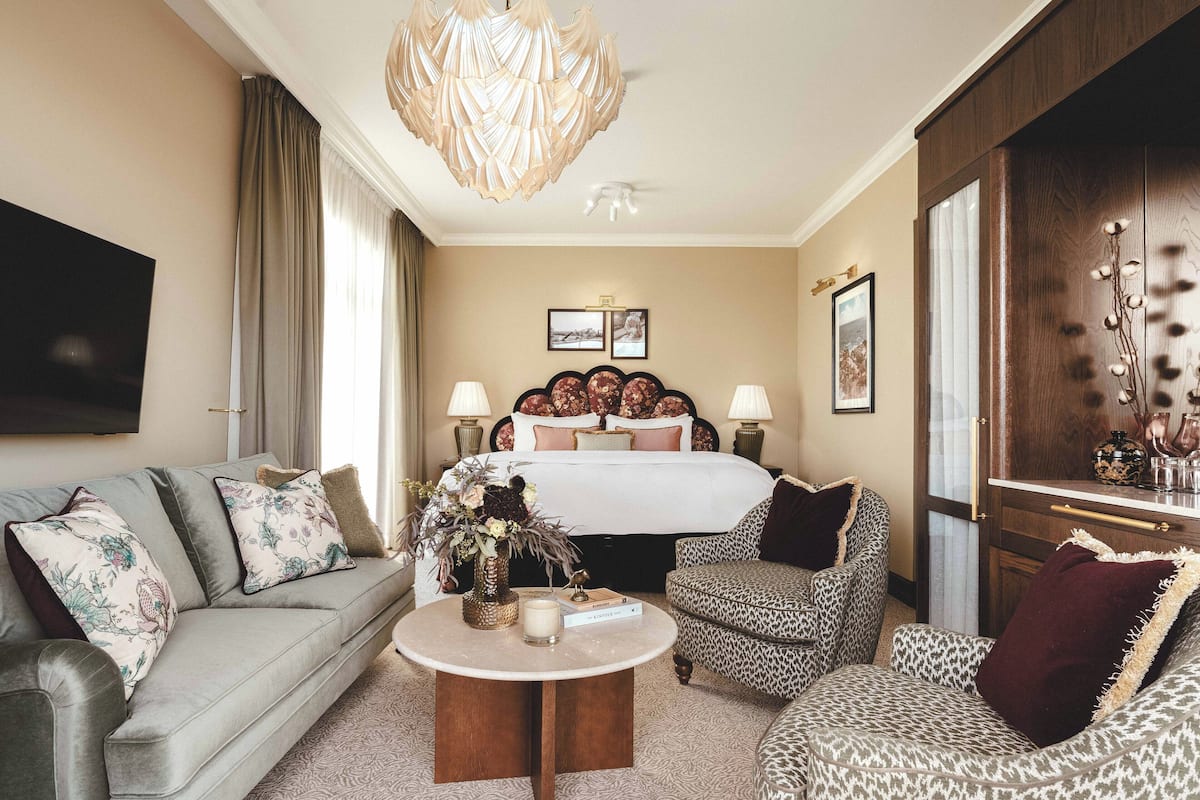 Una habitación de hotel con una cama, un sofá, una silla, una mesita de centro y un televisor.