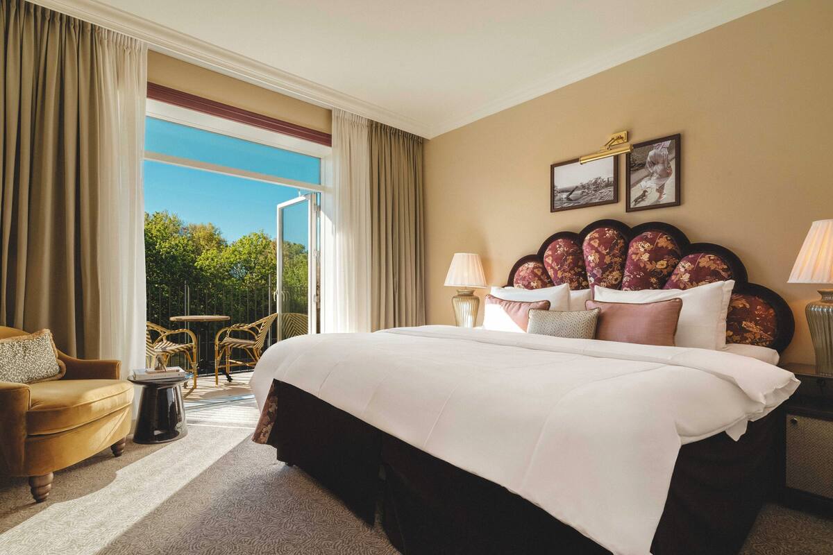 Habitación de hotel con una cama grande, un sofá, una mesita y vistas al exterior.
