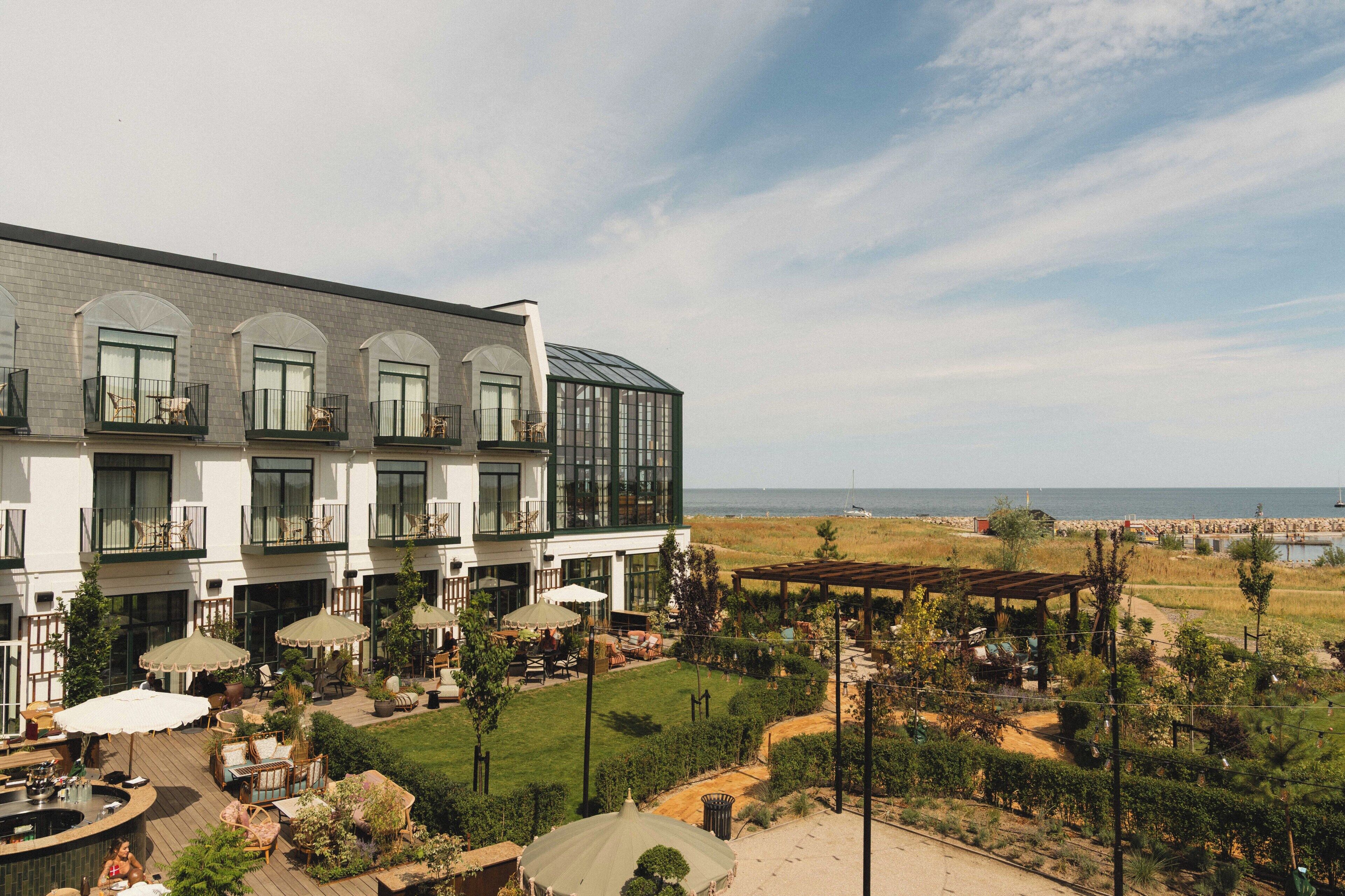 Um hotel com várias varandas, área de estar externa e vista para o mar.