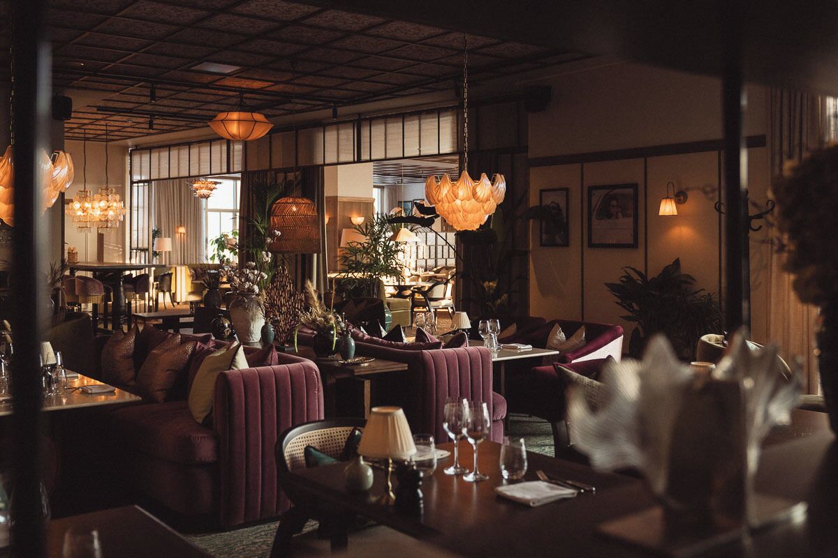 A restaurant with plush seating, pendant lighting, and a warm ambiance.