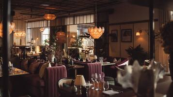 A restaurant with plush seating, pendant lighting, and a warm ambiance.