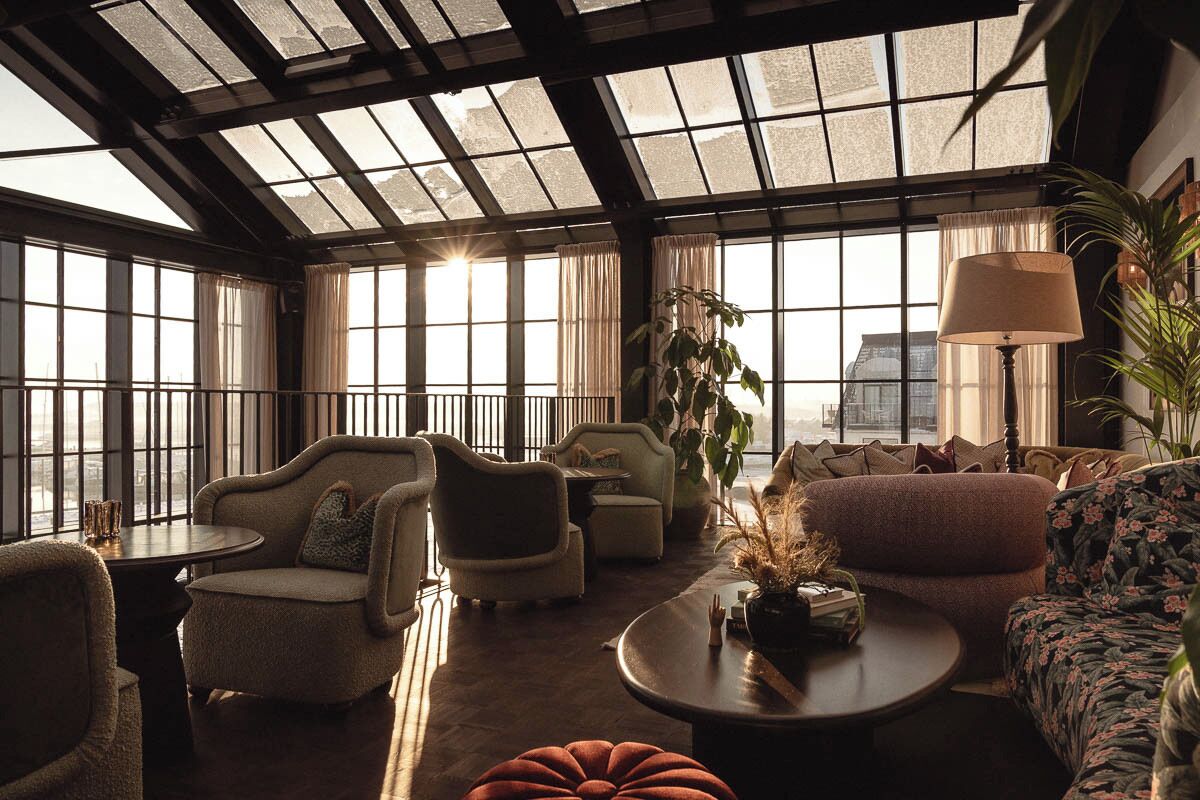 A spacious lounge with large windows, comfortable seating, and a ceiling with skylights.