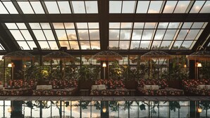 An indoor pool area with glass ceilings, lounge chairs, and potted plants.