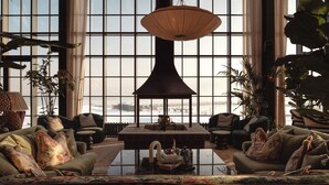 A spacious living room with large windows, a central coffee table, and multiple seating areas.