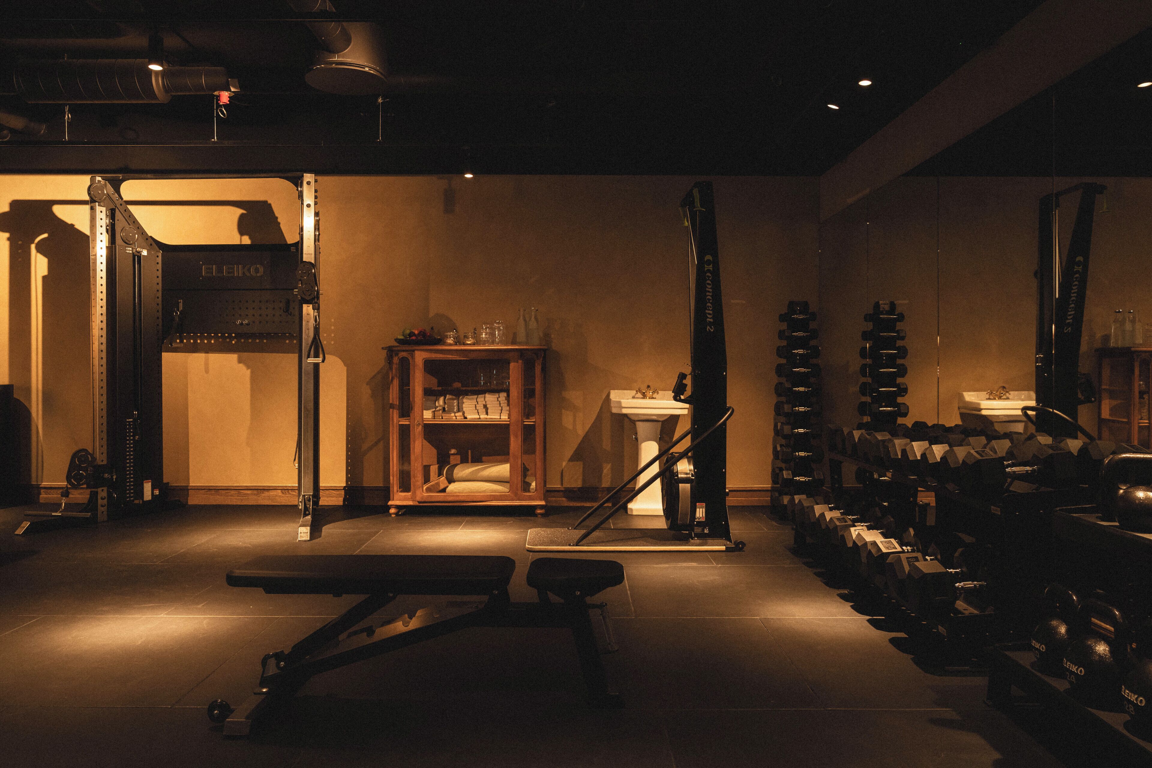 A gym with weightlifting equipment, benches, and a mirror.