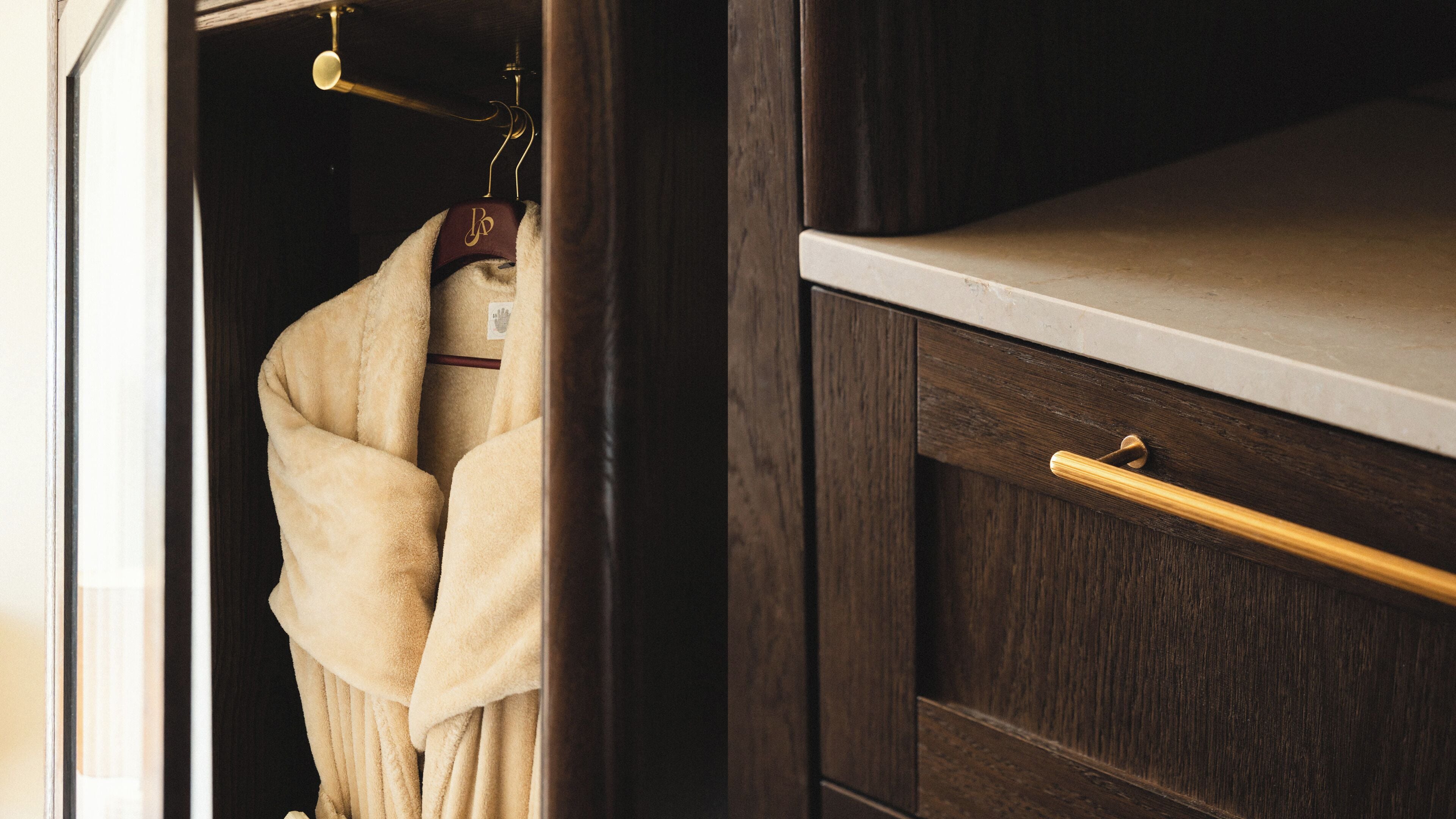 A wooden wardrobe with a drawer and a hanging space.