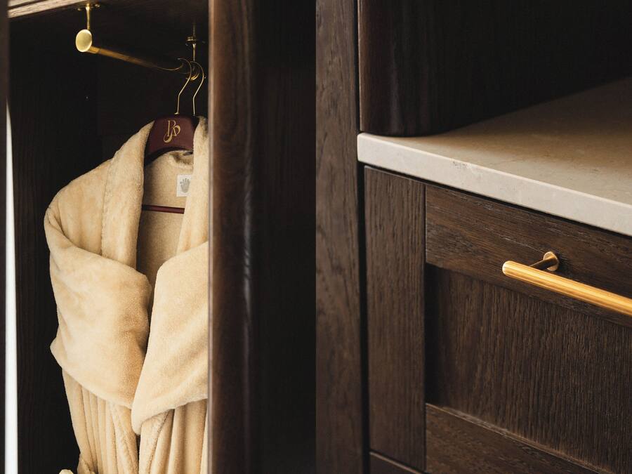 A wooden wardrobe with a drawer and a hanging space.