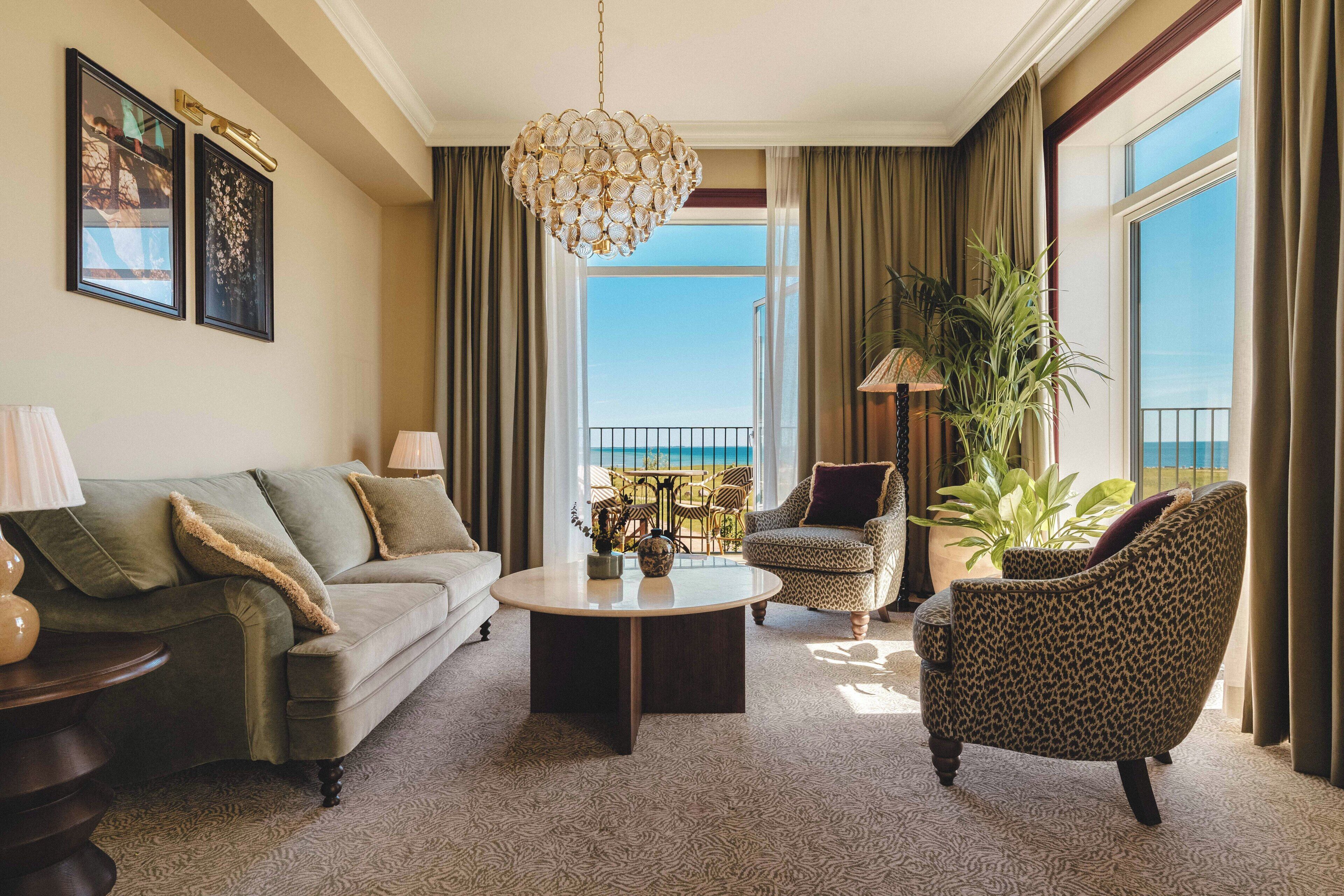 A living room with a sofa, armchair, coffee table, and a large window with a view.