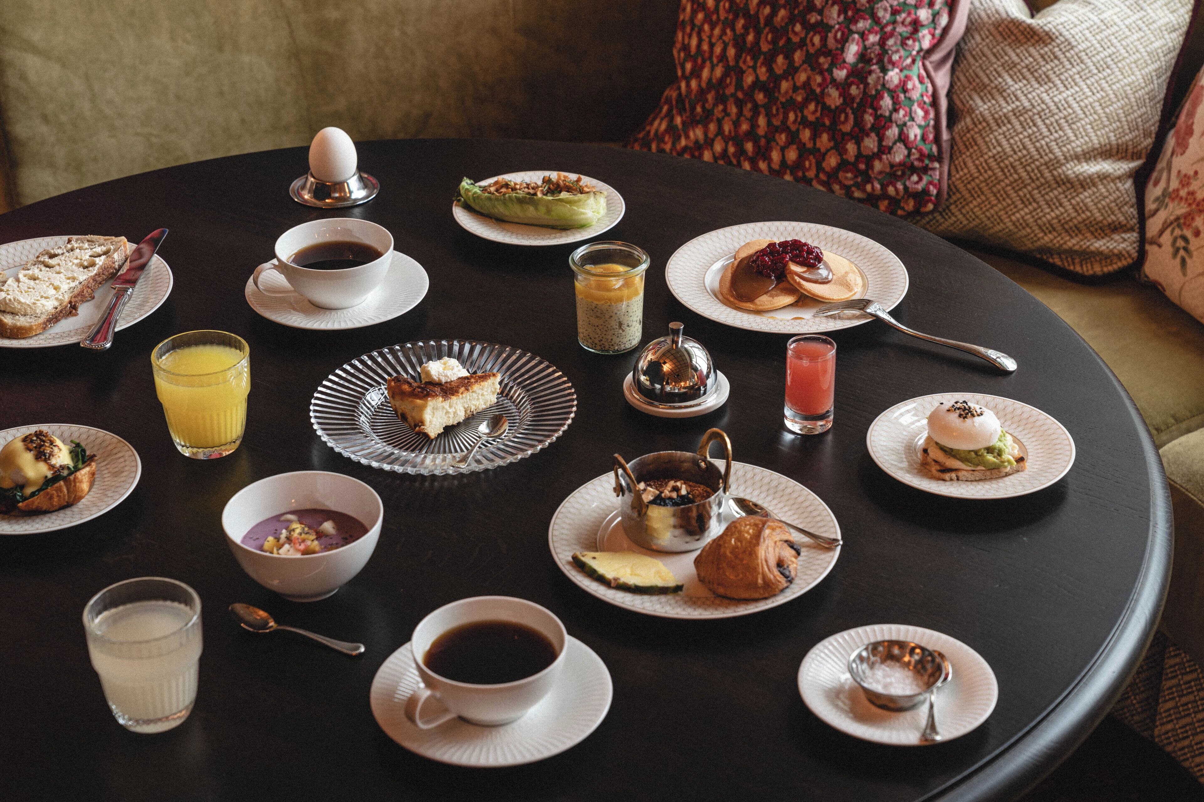 A round dining table with various breakfast items and beverages.