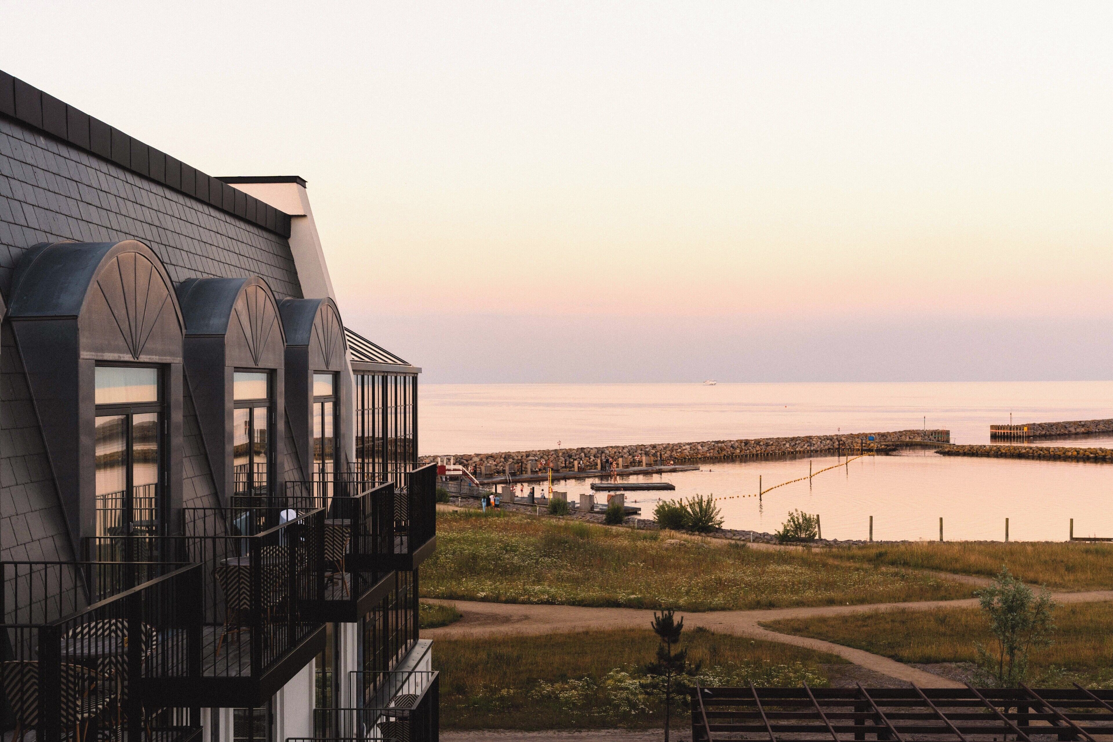 A modern building with a balcony overlooking a body of water and a rocky shoreline.