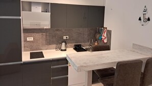 A modern kitchen with grey cabinets, a marble backsplash, and a white countertop. - Charming studio in enchanting Bečići with AC, WiFi (Bečići)