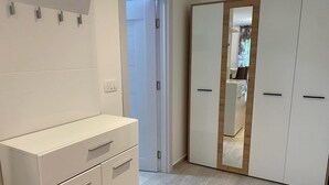 A room with a white wardrobe, a white dresser, and a mirror. - Charming studio in enchanting Bečići with AC, WiFi (Bečići)