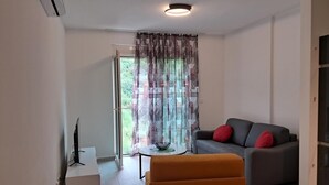 A modern living room with a grey sofa, a small round table, and a white cabinet. - Charming studio in enchanting Bečići with AC, WiFi (Bečići)