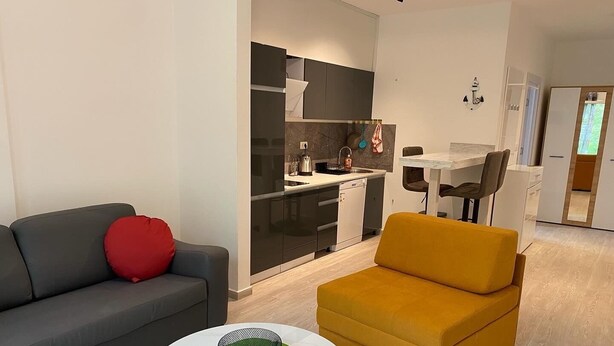 A modern living room with a grey sofa, a yellow armchair, and a round coffee table with a decorative bowl. - Charming studio in enchanting Bečići with AC, WiFi (Bečići)