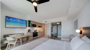 Ein modernes Hotelzimmer mit einem großen Bett, einer Essecke, einer Küche und einem begehbaren Kleiderschrank.