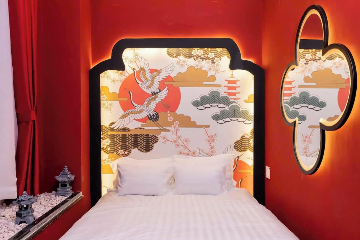 Un lit doté d’une tête de lit ornée d’un motif asiatique traditionnel, comprenant un oiseau et une pagode.