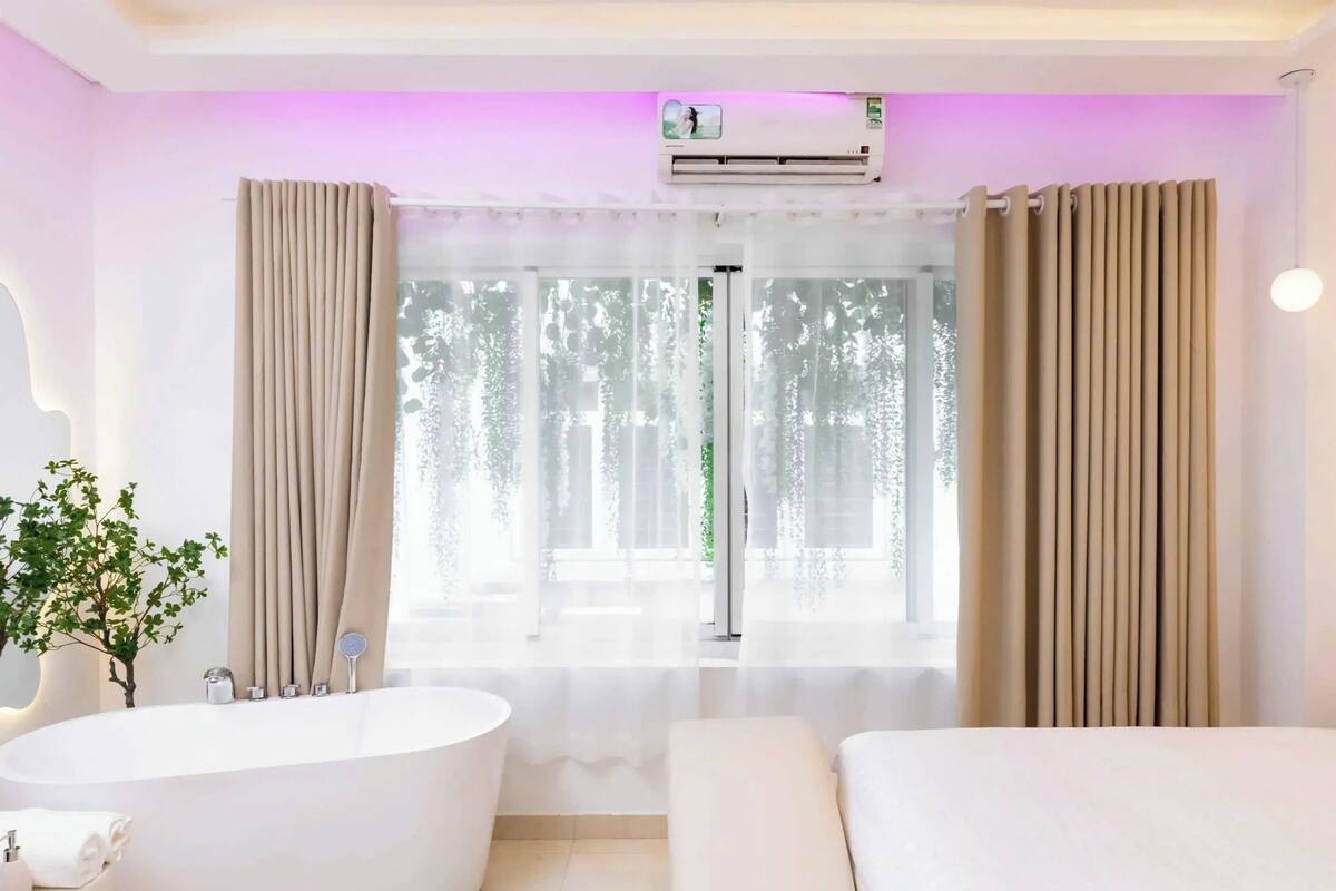 Une salle de bain moderne avec une baignoire sur pieds, un meuble-lavabo avec un miroir et une fenêtre avec des rideaux.