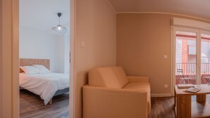 A bedroom with a bed, a chair, and a balcony with a railing. - Genius: An exceptional residence in Besançon in the heart of the Viotte business (BESANÇON)