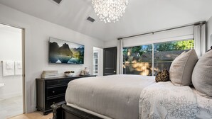 A bedroom with a large bed, a dresser, a chandelier, and a painting of a landscape. - The Lyndzee-Luxury Downtown Haven, Pool, Sleeps 16 (Dallas)
