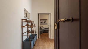 A hallway with a wooden ladder, blue storage bins, and a gray sofa in the background. - CS Termini National Apt No. 3 (Rome)