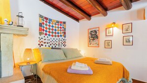 Une chambre à coucher comprenant un lit, une table de chevet, une lampe, une décoration murale et des tableaux encadrés.