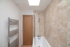 A bathroom with a shower, a bathtub, and a towel rack.