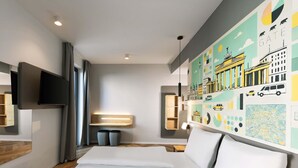 A modern hotel room with a large bed, a flat-screen TV, a map mural, and a wooden shelf. - B&B Hotel Berlin Airport-Nord (Berlin)