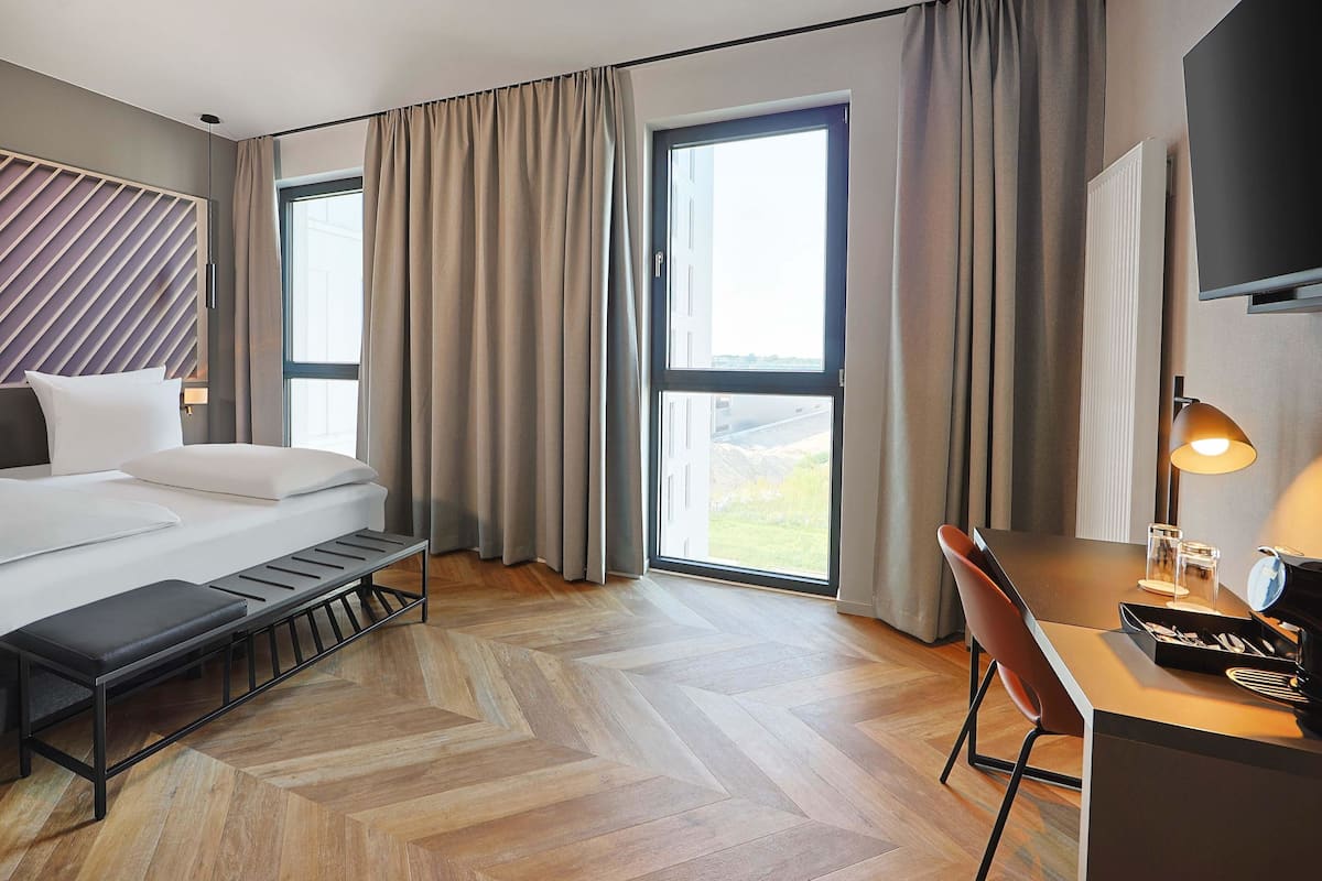 Une chambre d’hôtel moderne équipée d’un lit, d’un bureau, d’une chaise et d’un téléviseur.