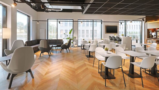 A modern office space with a herringbone wood floor, white and grey chairs, a sofa, and a coffee bar with a TV. - B&B Hotel Berlin Airport-Nord (Berlin)