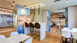Un moderno vestíbulo de hotel con área de bar, asientos y un mural de un paisaje urbano.