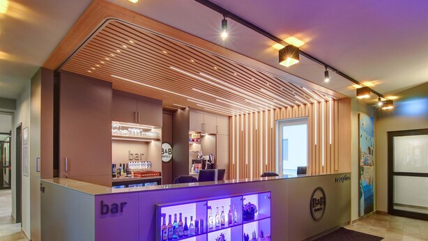 Un área de recepción con bar, una mesa de recepción y un cartel de paisaje urbano en la pared.