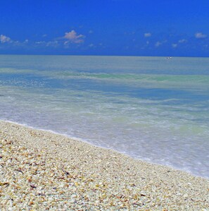 A beach with clear water and a pebbly shore.