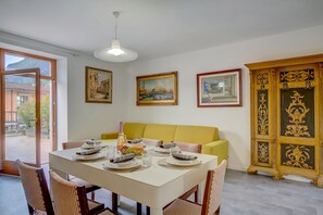 A dining area with a table set for four, a yellow sofa, and a cabinet with ornate designs. - Boutique Terrace Apartment In The Center (Riva del Garda)