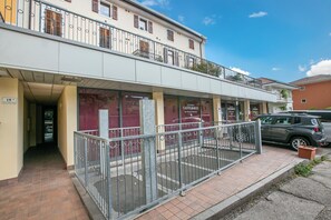 A two-story building with a ground-level entrance, a balcony with metal railings, and a car parked outside. - Boutique Terrace Apartment In The Center (Riva del Garda)