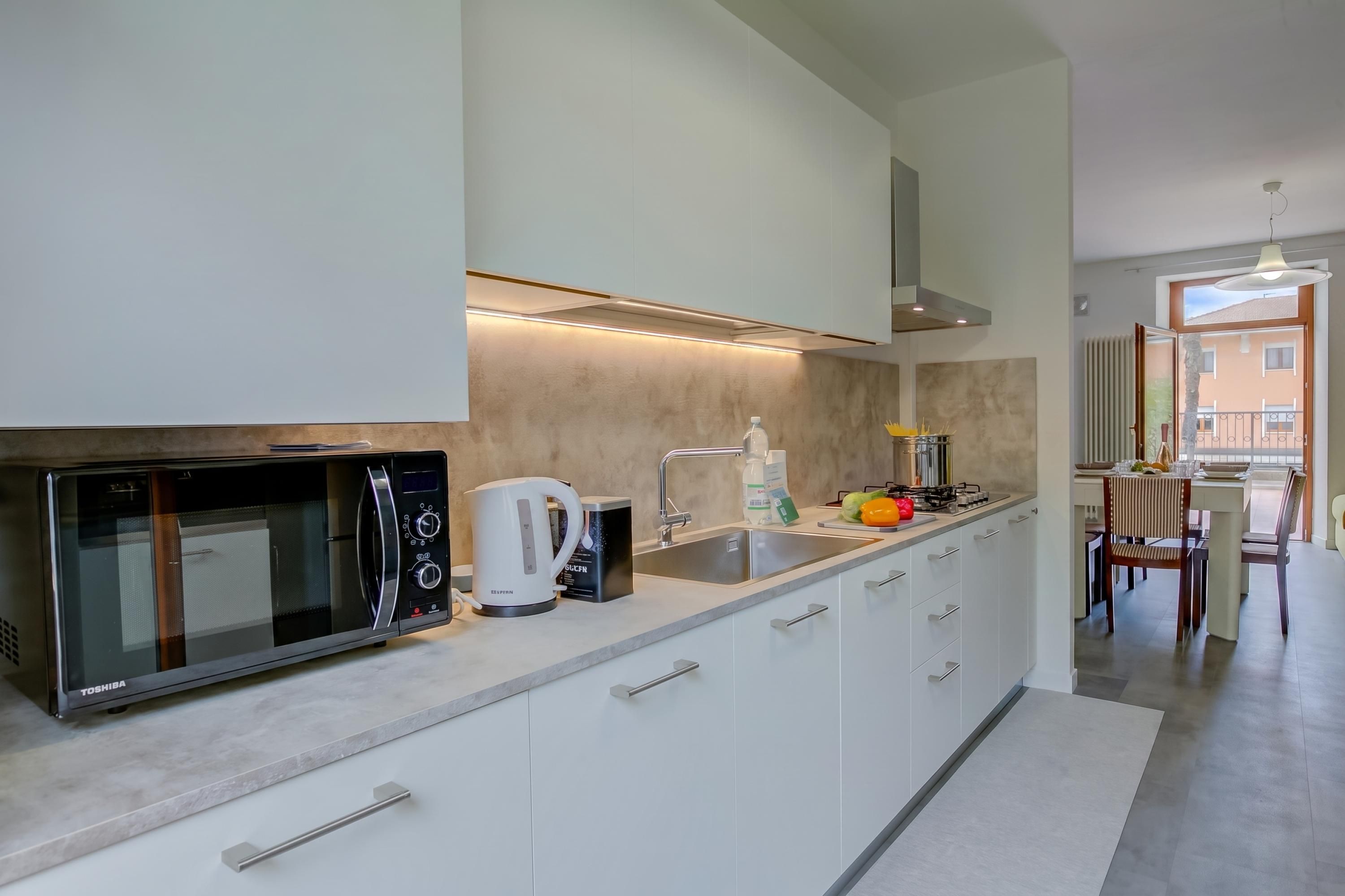 A modern kitchen with a built-in microwave, kettle, and sink.